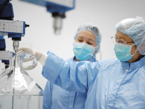 Two lab workers fill beaker
